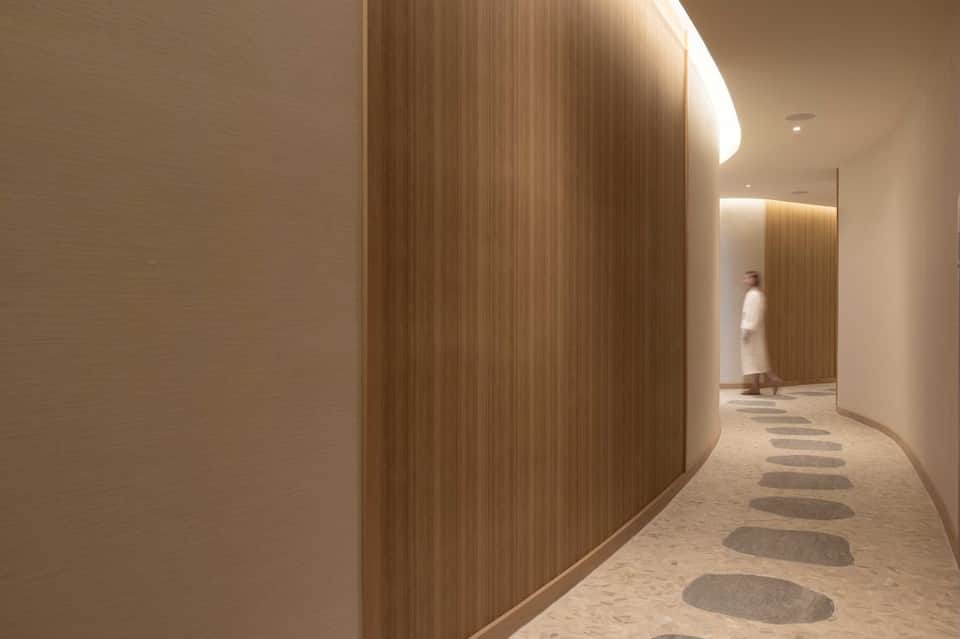 Minimalist hallway with wood-textured curved wall, ambient lighting, and stepping stone floor pattern