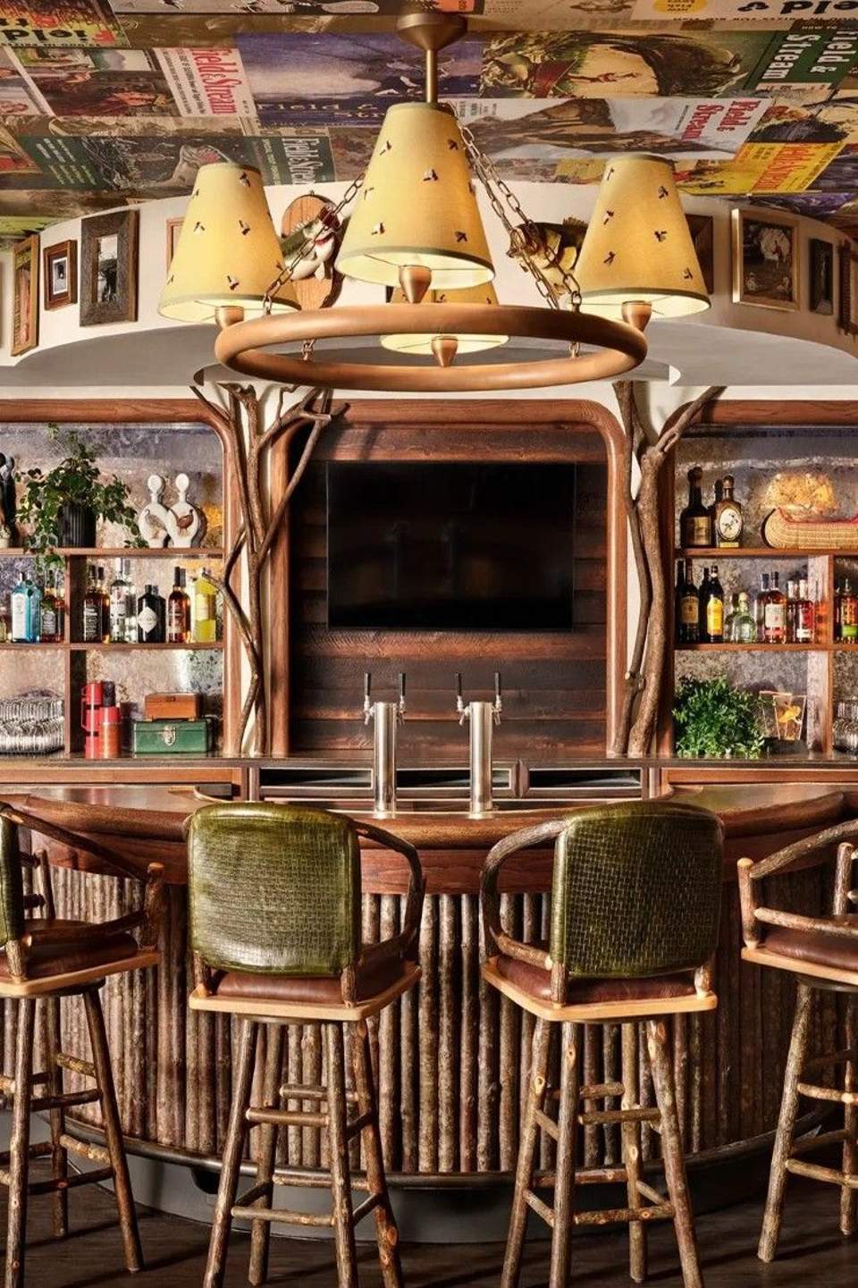Rustic bar interior with antler chandelier, mounted wildlife decor, shelved bottles, and wood accents