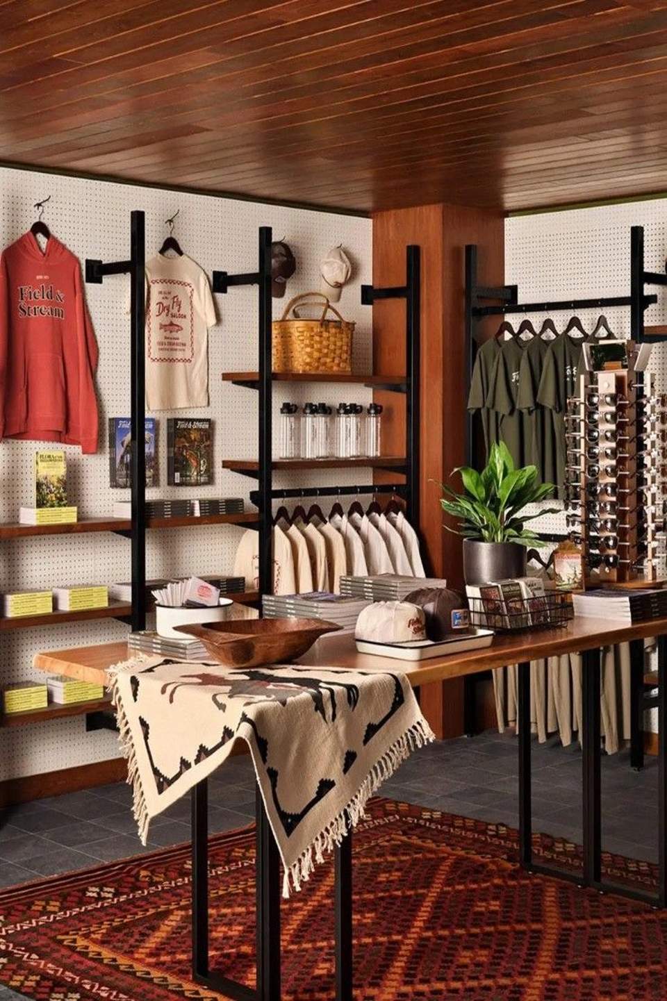 Retail shop display with wooden fixtures, pegboard walls, clothing, merchandise, and Native American rug