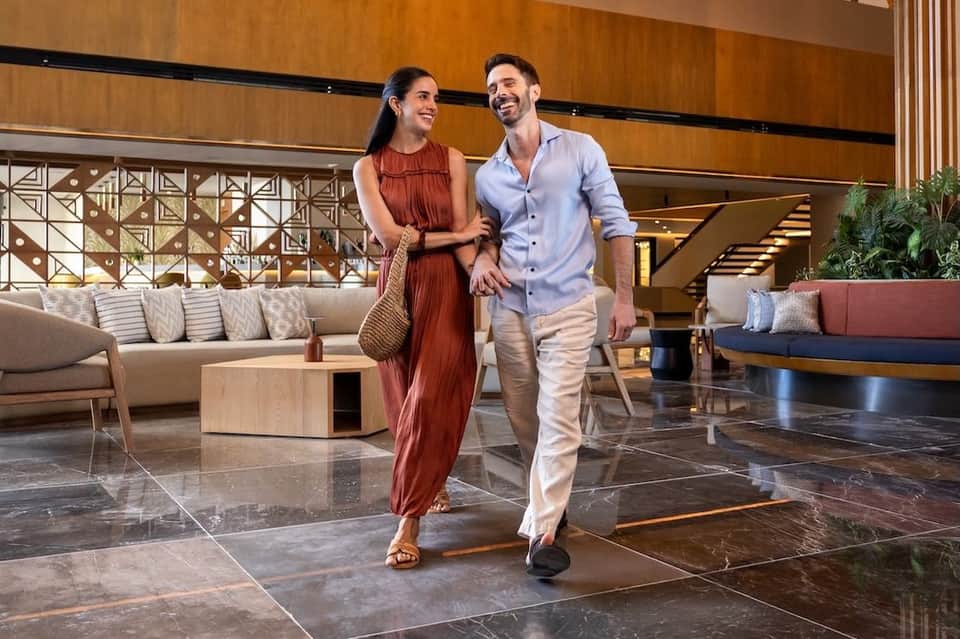 Couple walking through modern resort lobby with wooden ceiling and contemporary furniture