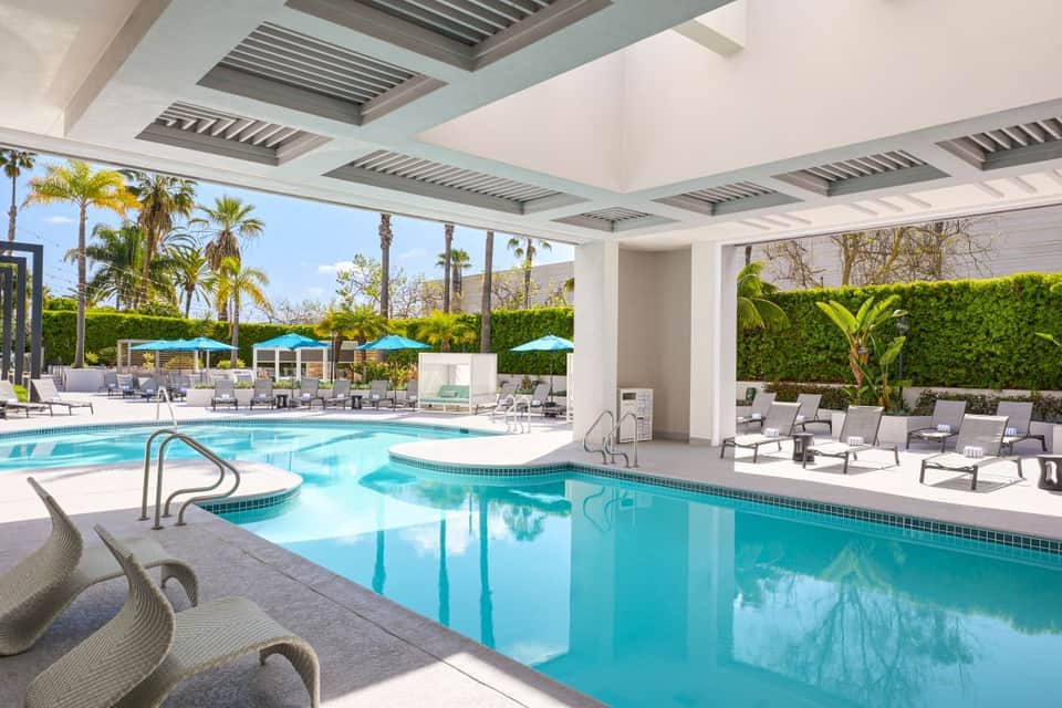 Indoor heated pool with spa jets, lounge chairs, and covered pavilion with modern ceiling in luxury resort