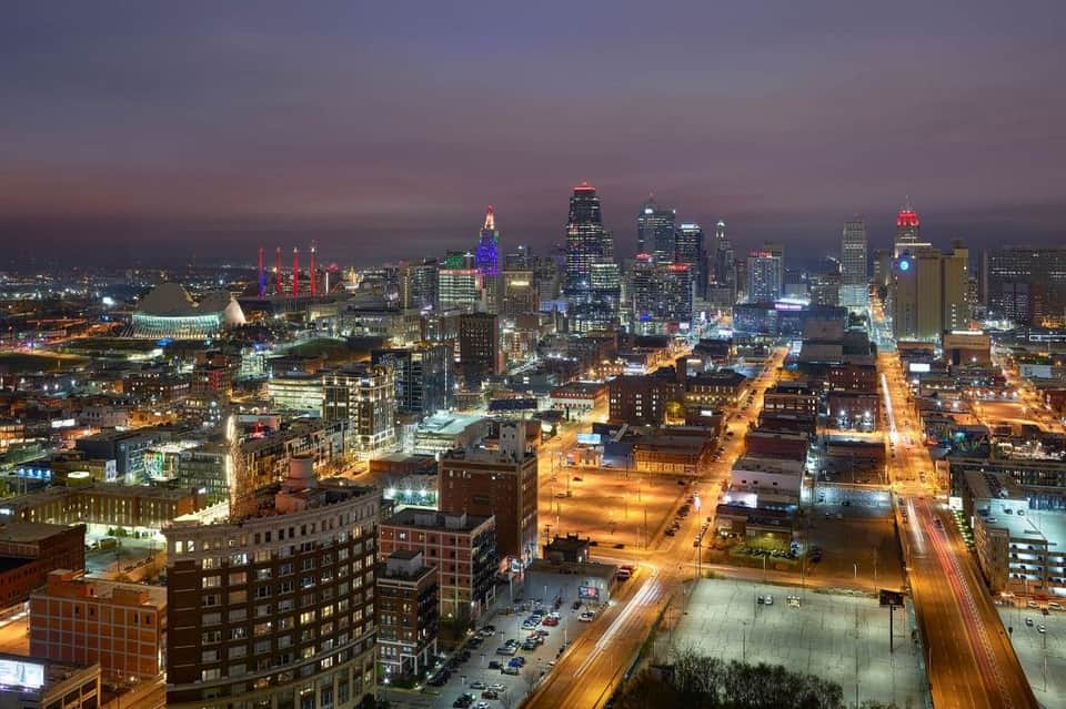 Kansas City skyline at dusk with illuminated skyscrapers, streets, and city lights