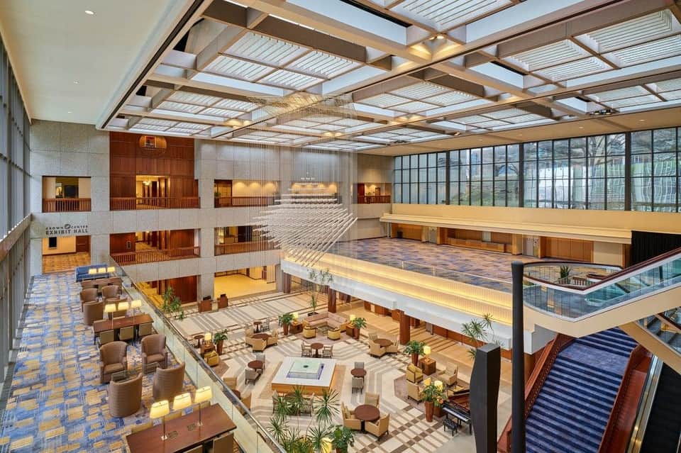 Luxurious multi-level hotel atrium with skylights, seating areas, plants, and wooden railings