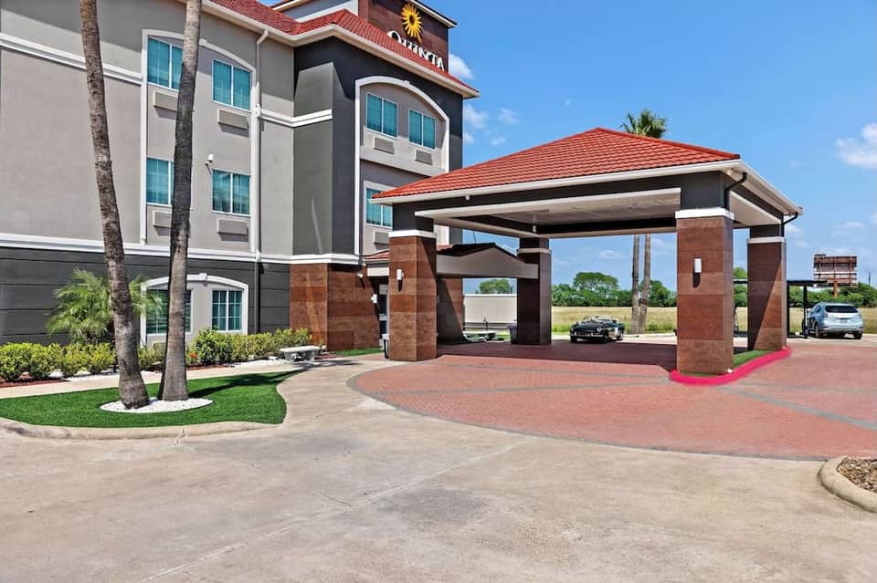Hotel exterior with brick entrance portico, red tile roof, and manicured landscaping