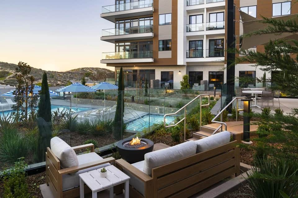 Residential fire pit lounge area overlooking tiered pools and hillside landscape at dusk