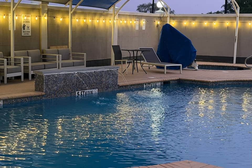 Indoor pool area with covered seating, loungers, and blue umbrellas