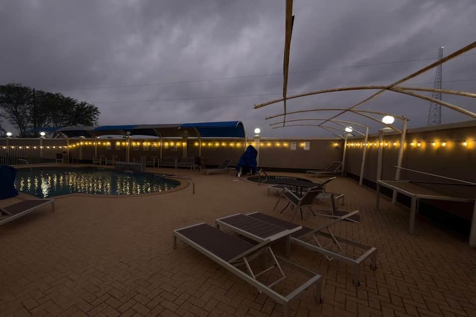 Pool deck with lounge chairs and retractable roof covering at dusk