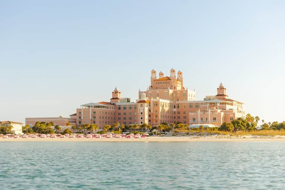 Pink Mediterranean-style beachfront resort with red umbrellas on sand
