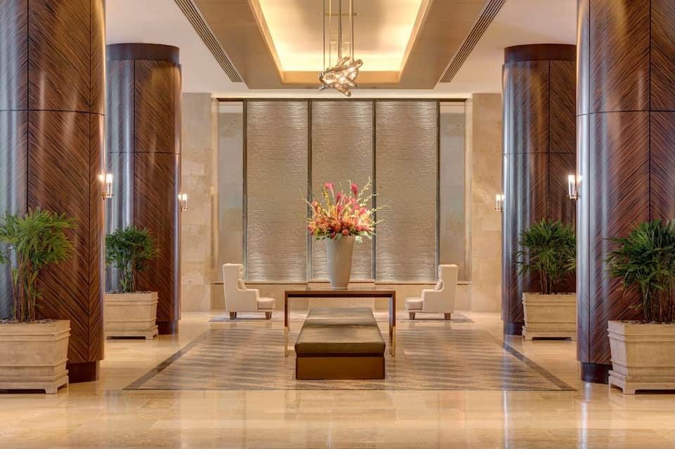 Modern spa lobby with symmetrical wooden pillars, potted plants, decorative elements, and geometric ceiling design