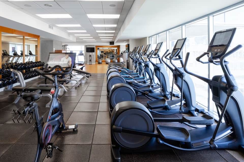 Well-equipped fitness center with cardio machines, exercise bikes, free weights, and large windows