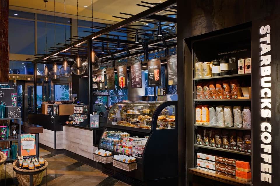 Starbucks coffee shop with black counter, displayed pastries, and shelving with coffee products