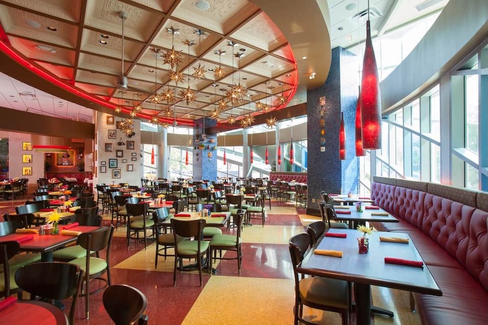 Vibrant restaurant with red ceiling accents, colorful tables, and artistic wall decorations