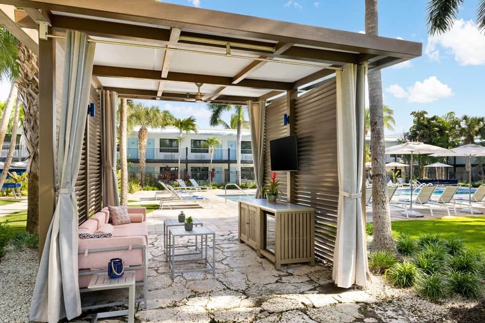 Modern pergola with pink seating overlooking a resort pool and manicured lawn