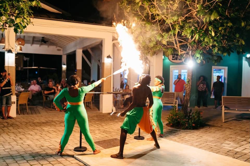 Fire performers entertaining guests at a nighttime poolside event with tropical decorations