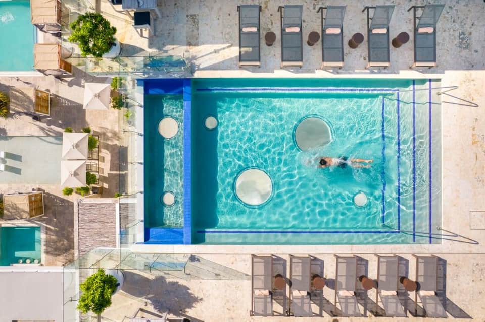 Overhead view of rectangular swimming pool with circular floating platforms and lounge chairs