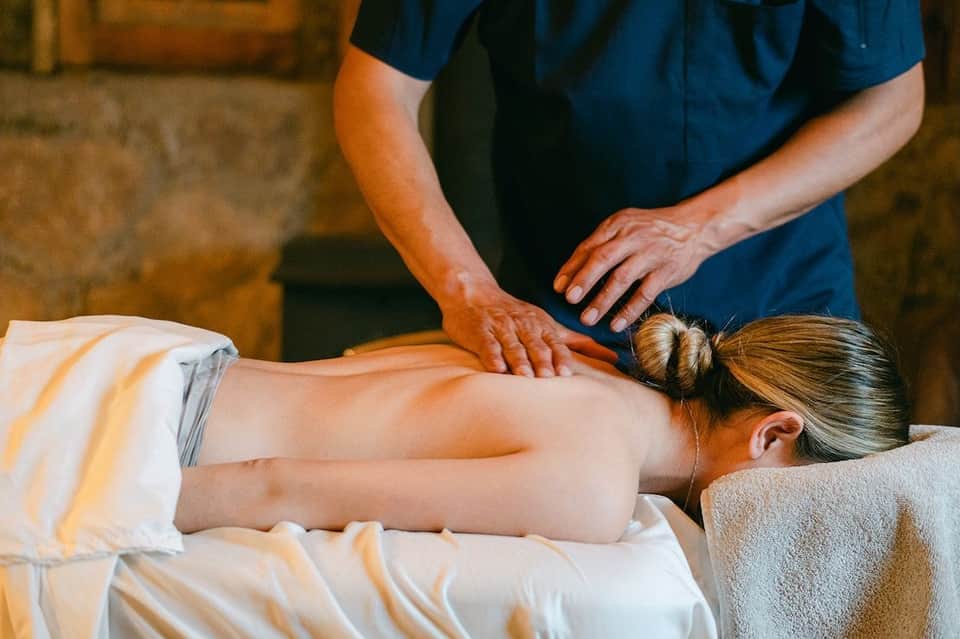 Male massage therapist performing deep tissue massage on female client's back
