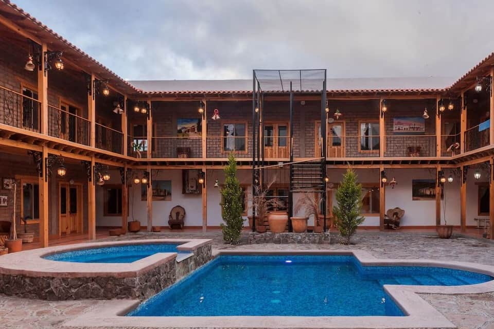 Colonial-style resort courtyard with terracotta brick architecture, two blue pools, and wooden railings