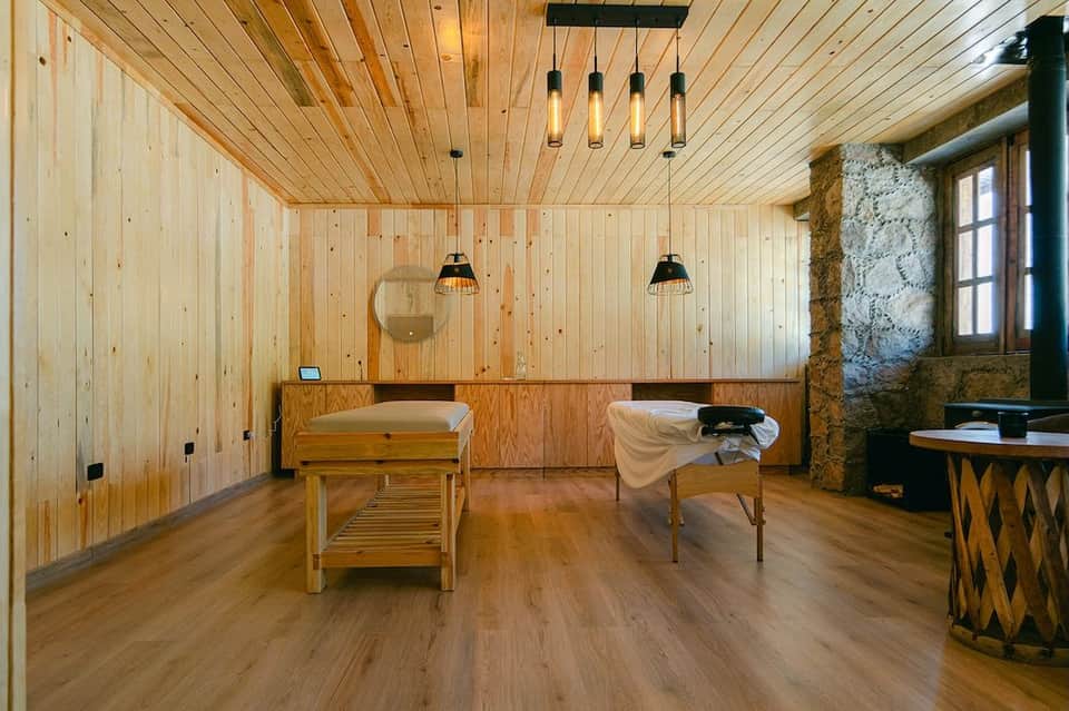 Spa treatment room with wooden tables, wood paneling, pendant lights, and stone accent wall