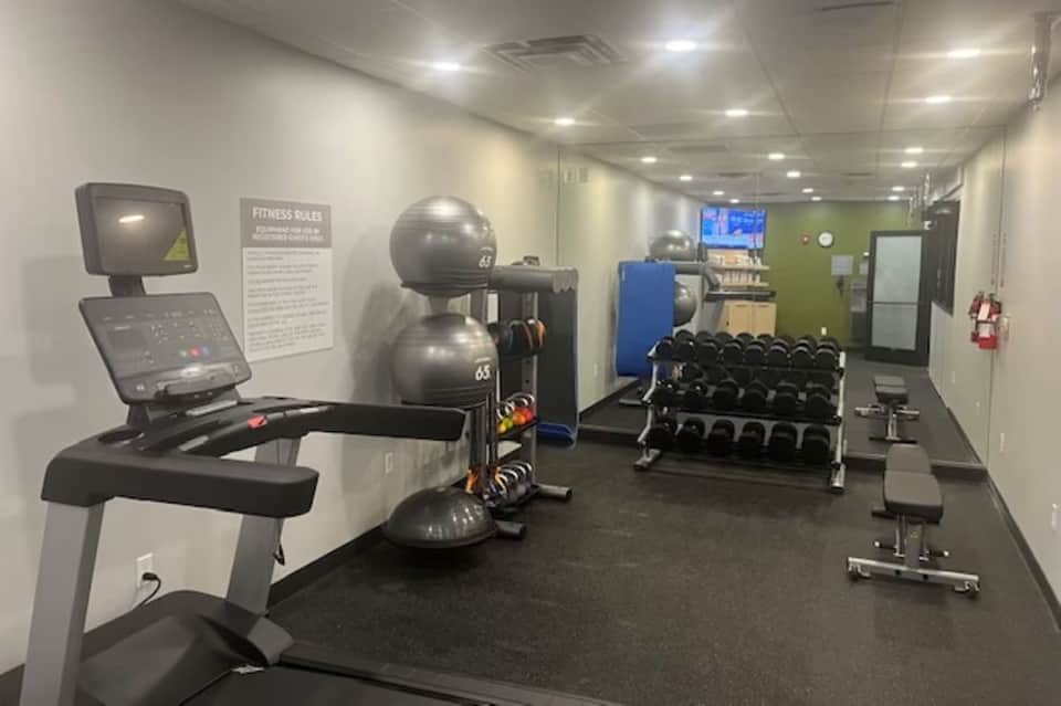 Modern fitness center with exercise bike, stability balls, dumbbell rack, and TV monitor