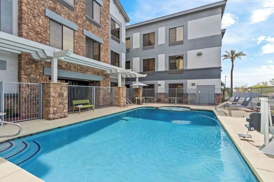 Resort outdoor pool with stone accent wall, lounge chairs, and multi-story hotel building