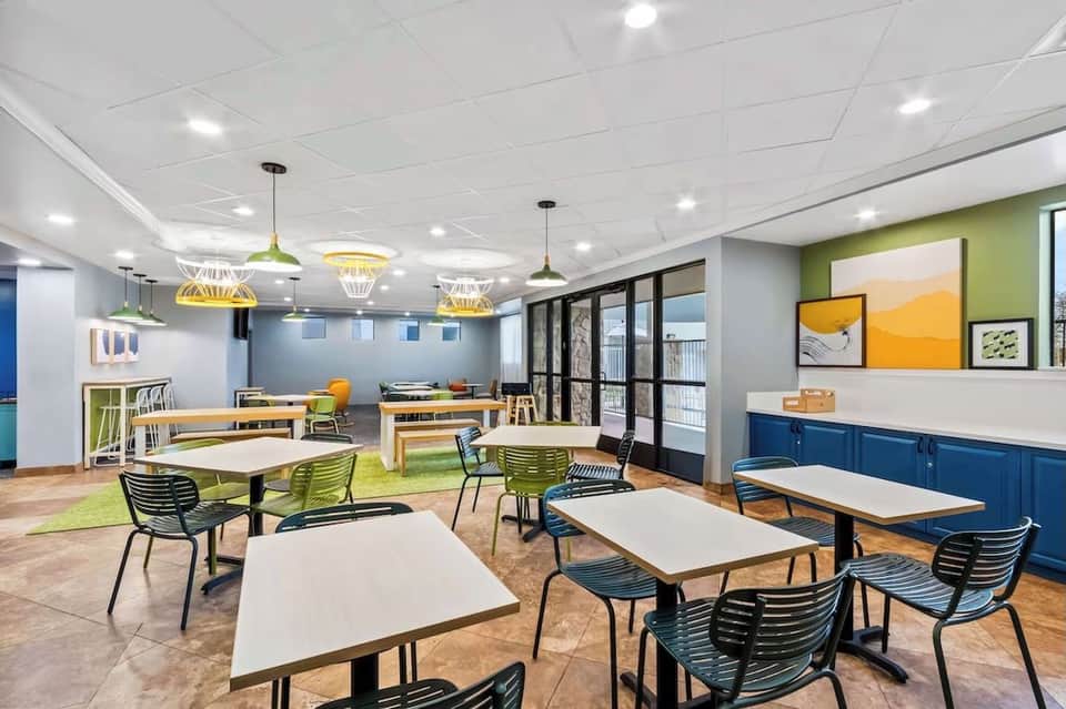 Contemporary lobby lounge with green and blue accents, pendant lighting, and communal seating