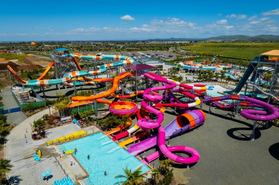 Overhead view of vibrant water park with colorful pink, orange, and yellow slides and pools