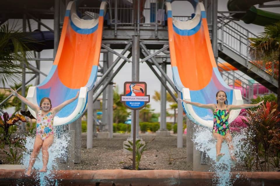 Twin orange water slides with children splashing at the base at a water park