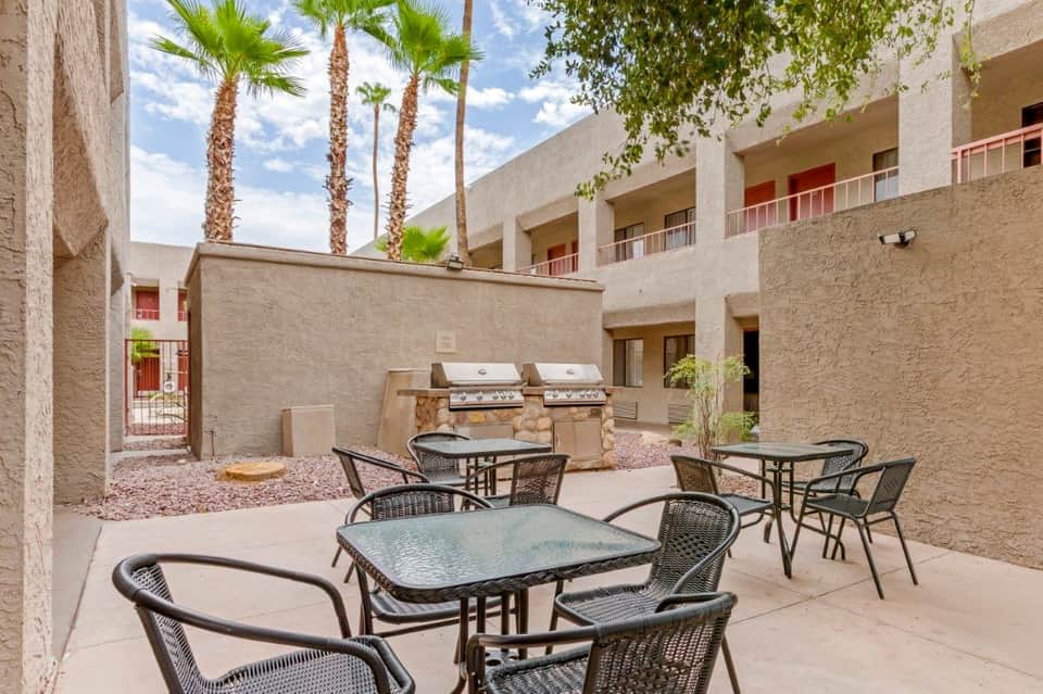 Courtyard with palm trees, patio seating, built-in grills, and multi-story residential building