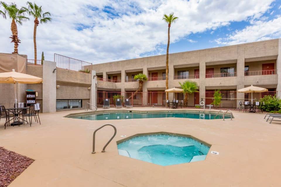 Resort courtyard with swimming pool, hot tub, palm trees, and multi-story building