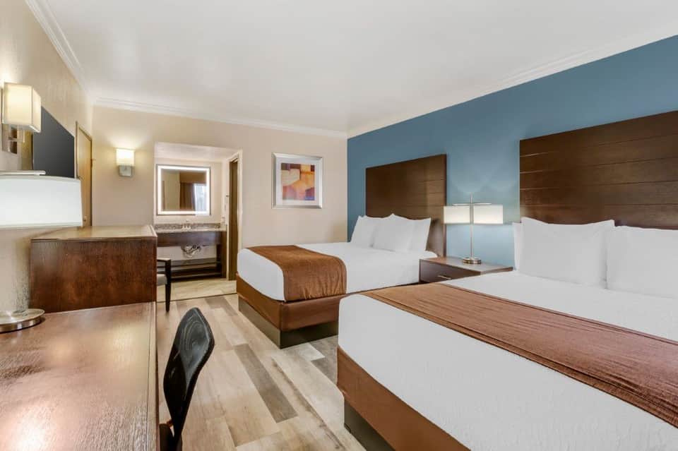 Hotel guest room with two queen beds, blue accent wall, and modern furnishings