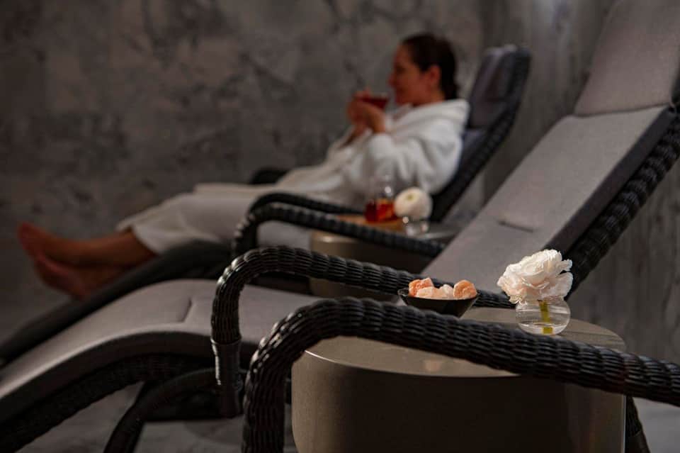 Spa lounge with reclining chairs, white flowers, and aromatherapy candles