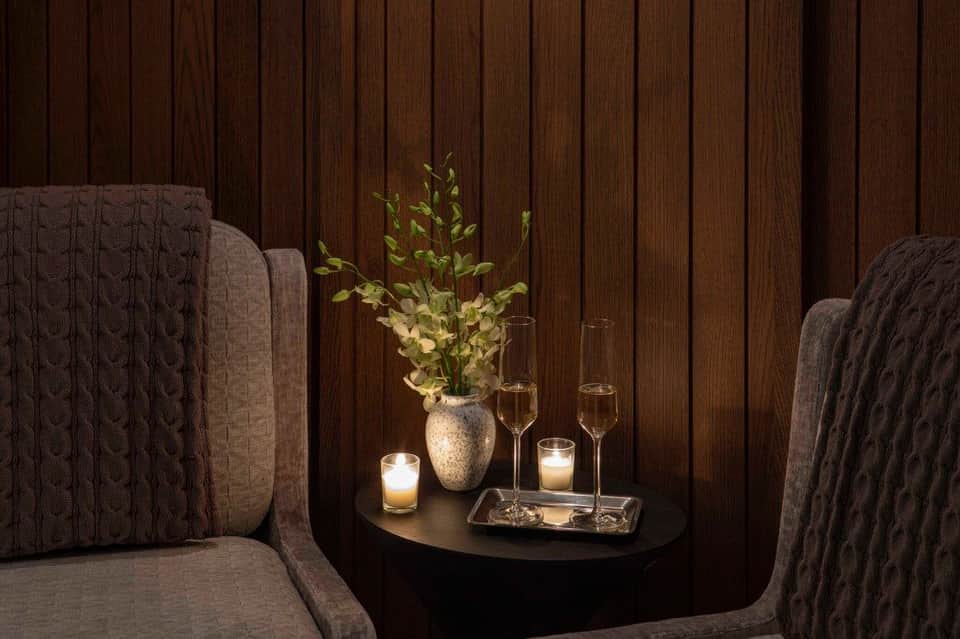 Intimate spa seating nook with textured chairs, fresh flowers, and ambient candlelight