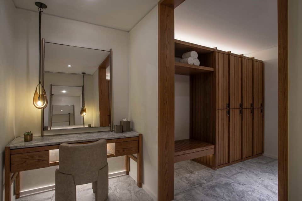 Luxury spa bathroom with wooden vanity, large mirror with pendant lights, and wooden closet cabinetry