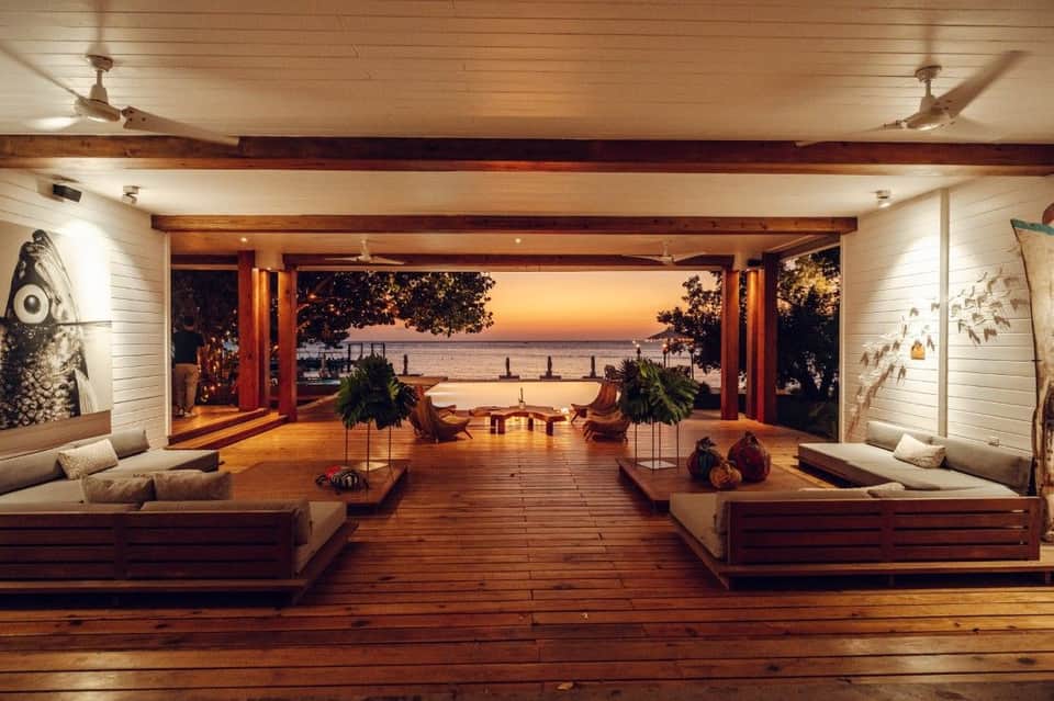 Open-air beachfront pavilion with wooden decking, sunset views, and contemporary furniture