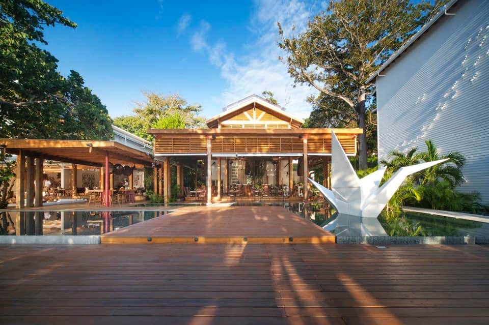 Contemporary beachfront resort with multiple wooden structures, decking, and white bird sculpture