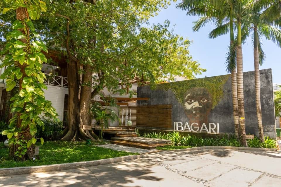 IBAGARI resort entrance with tropical vegetation, palm trees, and modern architectural signage on concrete wall