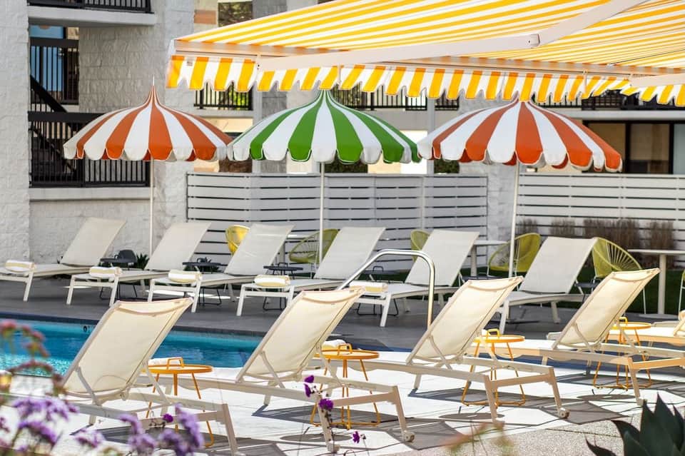 Pool area with striped umbrellas in orange, green, and white over loungers