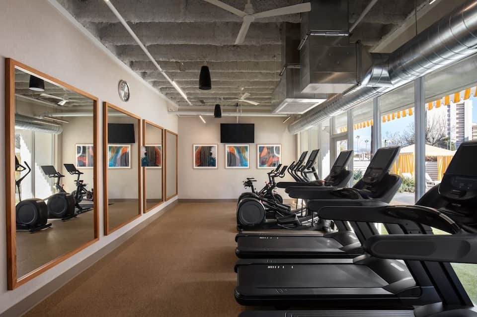 Bright fitness studio with treadmills, exercise bikes, and glass partition walls