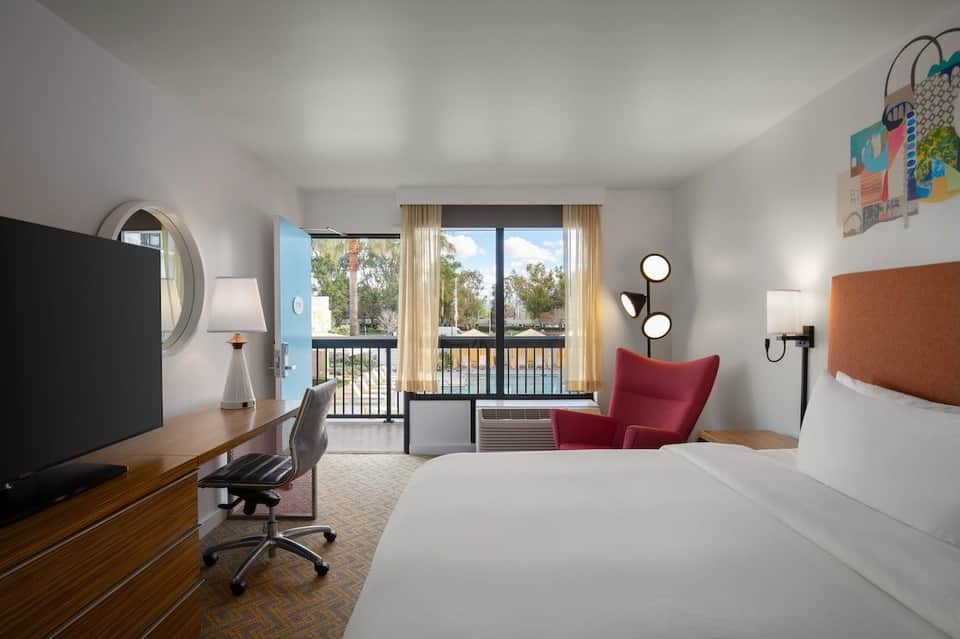 Modern hotel room with balcony view, work desk, and contemporary furnishings