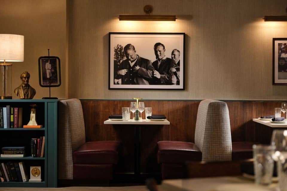 Intimate dining nook with booth seating, framed photographs, and wooden paneling accent wall