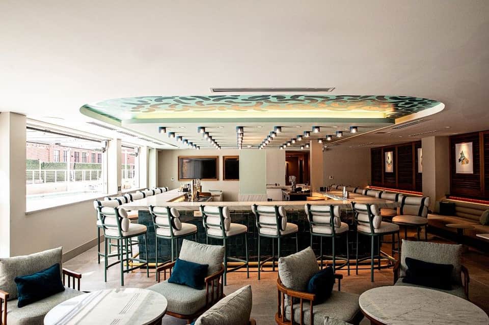 Hotel lounge with circular bar, decorative ceiling art, casual seating, and modern design elements