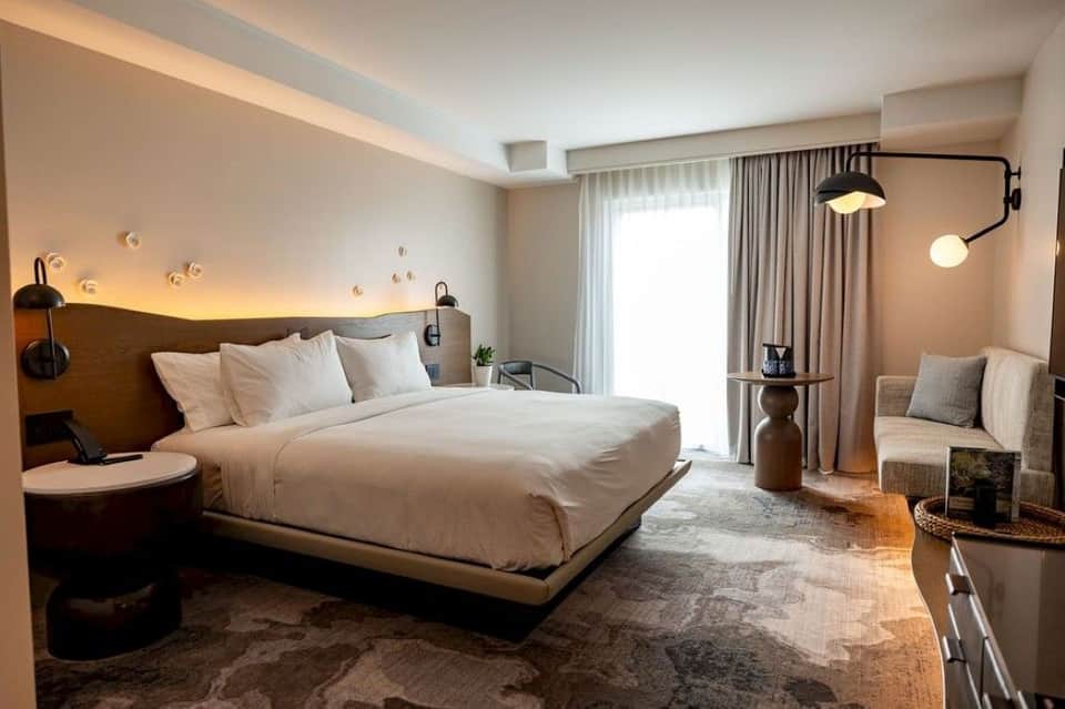 Luxury hotel suite featuring king bed, warm lighting, floor-to-ceiling windows, and contemporary décor