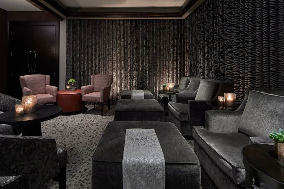 Contemporary lounge with dark textured walls, scattered seating, ambient lighting, and decorative pillows