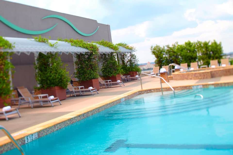 Resort swimming pool with lounge chairs, shade canopy, and scenic overlook of landscape