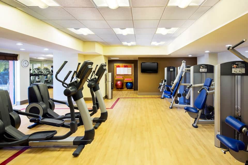 Bright fitness center with cardio equipment, exercise bikes, weight machines, and motivational sports imagery on walls