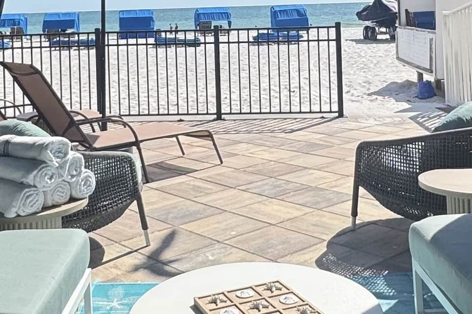 Beachfront deck with lounge chairs, rolled towels, and ocean view behind metal railing