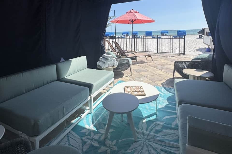 View from inside cabana overlooking beach with red umbrella, lounge chairs, and ocean
