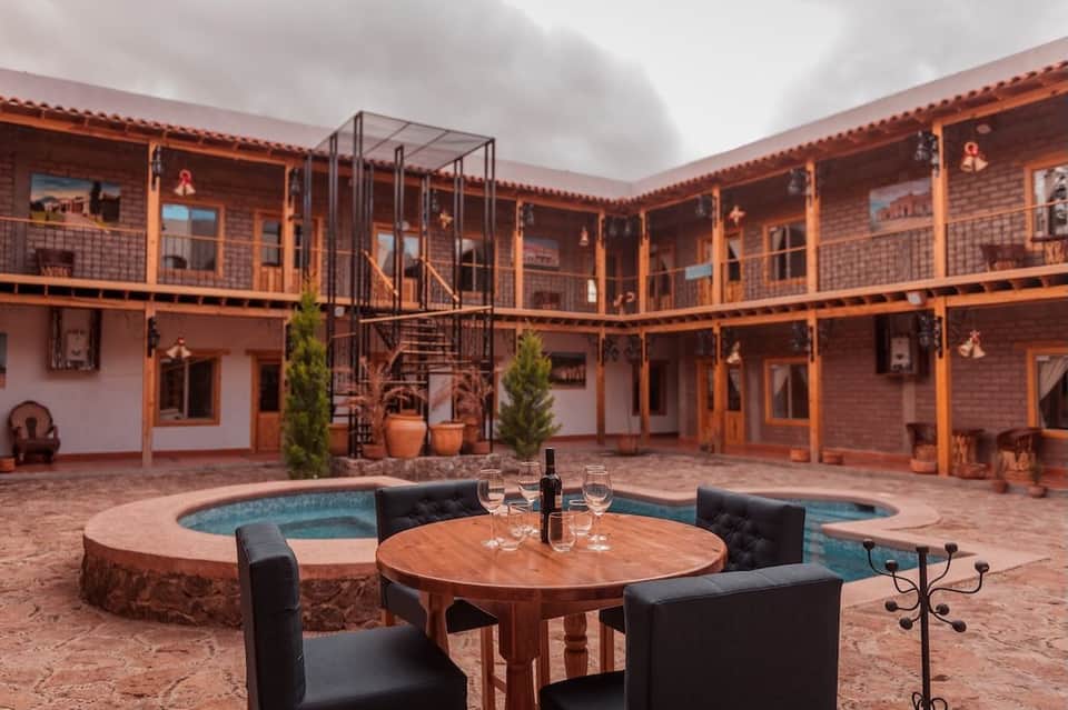 Colonial-style courtyard with central pool, wooden railings, brick buildings, and wooden table