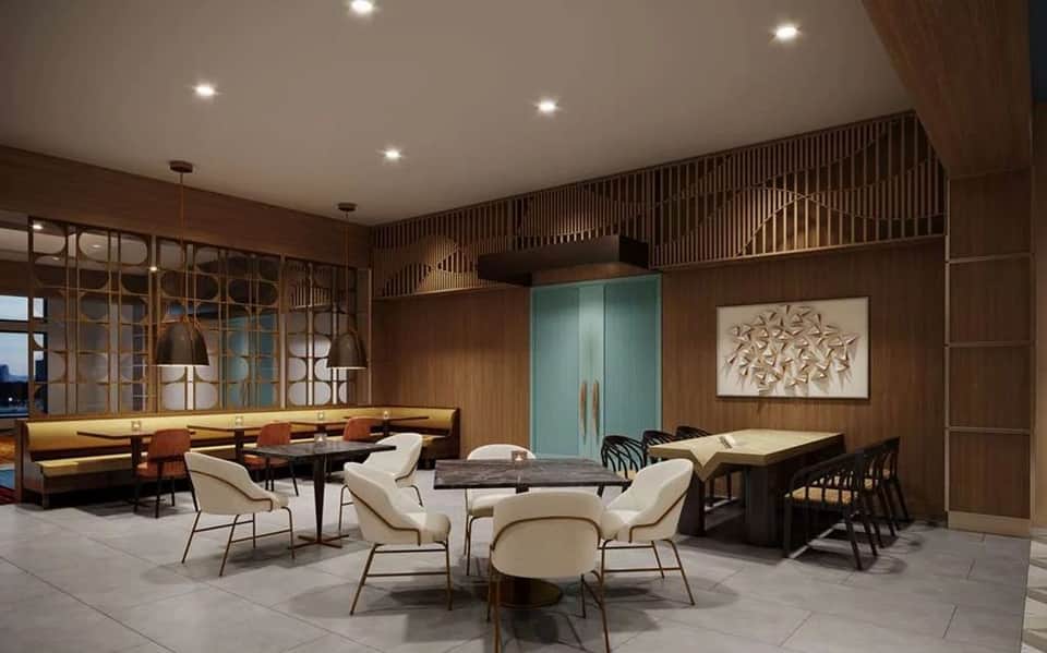 Upscale hotel lounge with wood paneling, cream chairs around marble table, and ambient lighting throughout spacious room