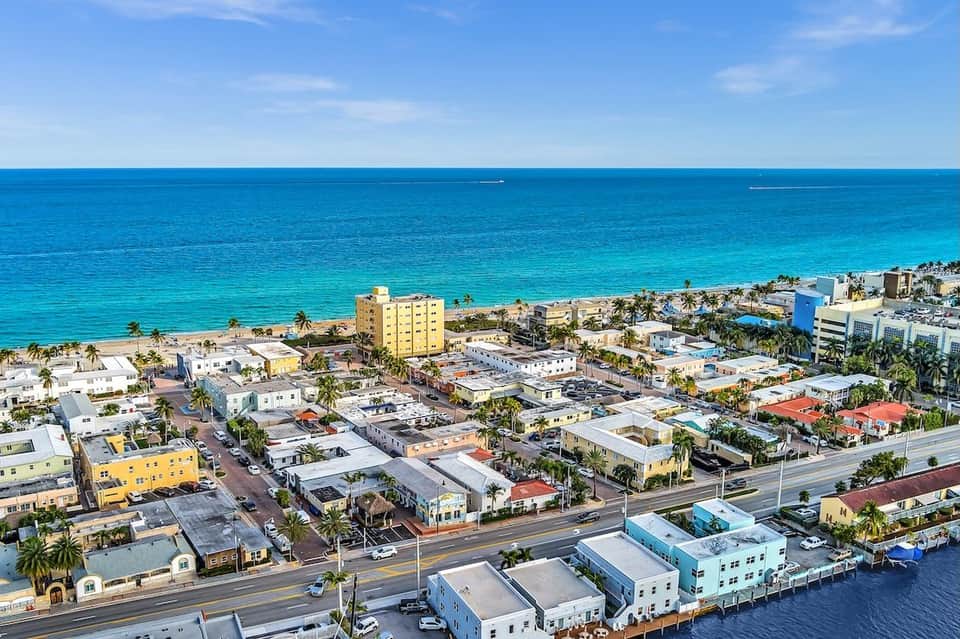 Aerial view of colorful beachfront resort town with turquoise ocean and palm trees